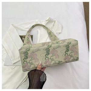 Detailed view of traditional Chinese embroidery and jacquard texture on green bucket bag