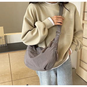 Vue détaillée d'un grand sac croissant en nylon gris avec bandoulière réglable sur modèle