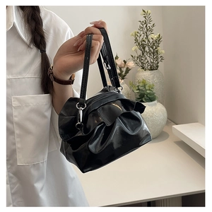 Detail of black pleated PU leather handbag with drawstring ruffles and silver hardware