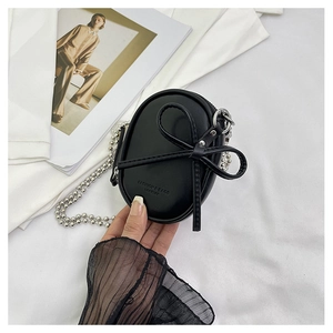 Primer plano de mini bolso ovalado negro con lazo de cuero y cadena de cuentas de metal plata