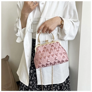 Detailed view of light pink evening bag featuring embossed hearts and a golden top handle