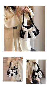 Detailed view of black corduroy shoulder bag featuring a large white satin bow and drawstring
