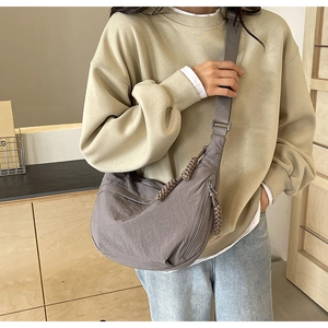 Gros plan du sac en nylon gris avec le détail de la fermeture éclair en corde tressée main