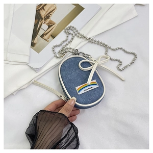 Primer plano del mini bolso denim con lazo blanco y correa de cadena de bolas plata