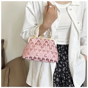 Close-up of pink evening bag featuring heart patterns, gold top handle and chain strap