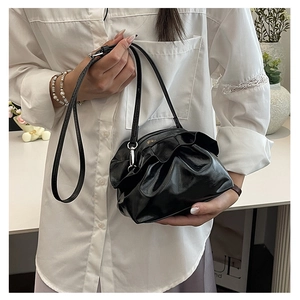 Close-up of black cloud pleated handbag with ruffled edges and glossy leather texture