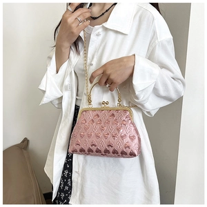 Detail of pink metallic heart embossed clutch bag with gold handle and chain strap