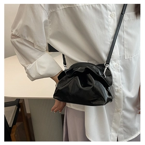 Detail showing the pleated black leather texture and metal rings of the cloud bag crossbody