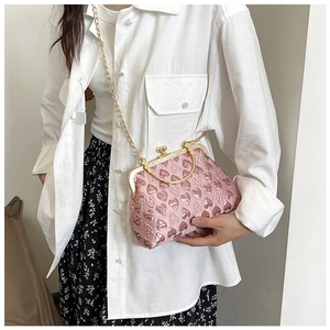 Detail of pink heart-patterned satin evening bag with golden metal frame and chain strap