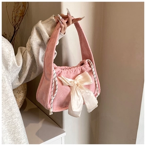Detail of pink corduroy handbag with a large white satin bow and drawstring closure