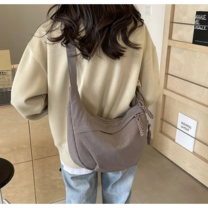 Vue arrière d'un grand sac bandoulière croissant en nylon kaki sur une tenue sobre