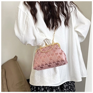 Close-up of pink heart-patterned evening bag with gold metal clasp and chain strap