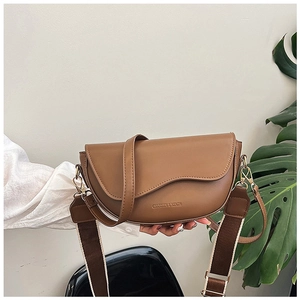 Close-up of brown saddle bag with matte leather finish and gold hardware detail