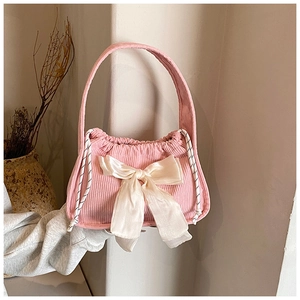 Detail of pink corduroy handbag featuring a large satin bow and drawstring design