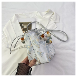 Détail du sac seau en jacquard avec motifs papillons et poignée en perles colorées