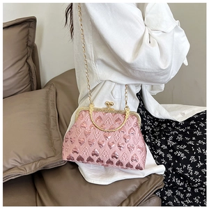 Close-up of pink heart-jacquard fabric evening bag with gold chain strap on sofa