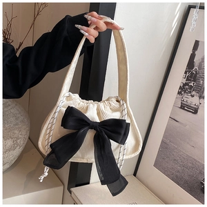 Detailed close-up of corduroy bag with large black chiffon bow and drawstring closure