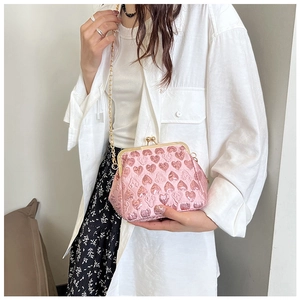 Close-up of heart-embossed pale pink crossbody bag with vintage gold metal clasp and chain