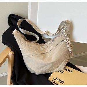 Détail du sac croissant en nylon beige avec bandoulière réglable et détails de zip