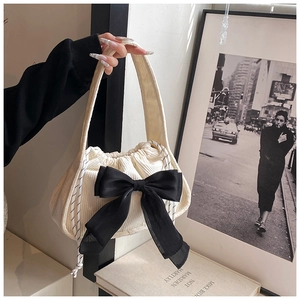 Detail of beige corduroy handbag with large black mesh bow and drawstring closure