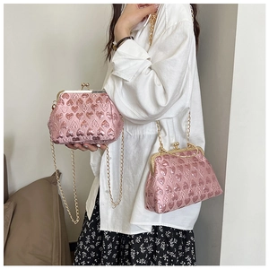 Detail of pink heart-embossed clutch bags with gold metal chain straps and clasp closures