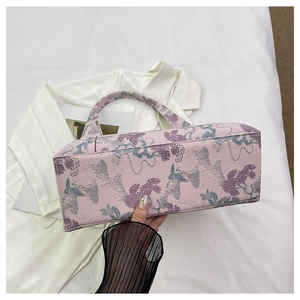 Detail of pink fabric handbag showing intricate floral and bird embroidery with rectangular base