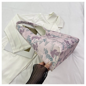 Close-up of pink jacquard fabric with vintage floral embroidery on a bucket bag