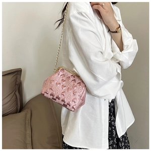 Pink heart-embossed crossbody bag with vintage gold clasp and elegant chain strap on a model