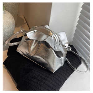 Detail of silver metallic crossbody bag featuring trendy pleated top and modern finish