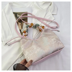 Détail du sac à main en tissu jacquard rose avec motif de jardin chinois et anse perle