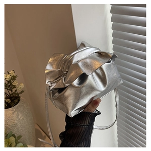Detail of silver metallic ruffled shoulder bag with pleated leather texture and slim strap