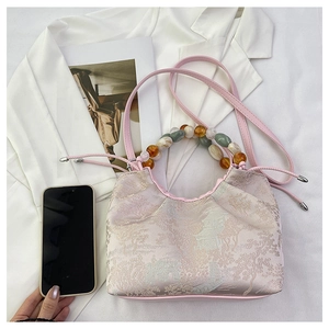 Détail du sac à main en soie rose clair avec broderie de paysage chinois et perles colorées