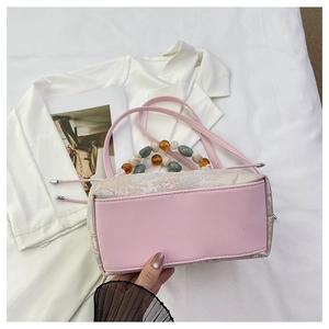 Détail du sac à main rose style chinois avec broderie florale et poignée en perles colorées
