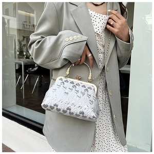 Detail of silver evening bag with heart-shaped embossing and metallic flower handle
