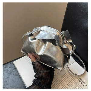 Detail of silver pleated cloud bag with shiny metallic texture and slender shoulder strap