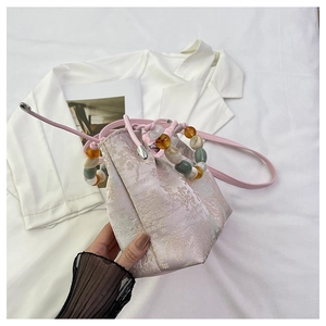 Détail du sac seau rose brodé avec poignée en perles ornée et motifs en soie de style oriental