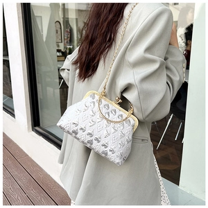Detail view of heart-textured crossbody bag with gold handle on a model's grey suit