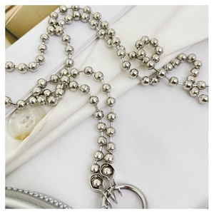 Detalle de cadena de bolas de metal plateado con cierre sobre tela blanca suave