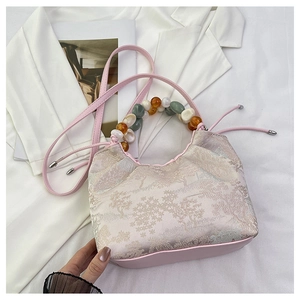 Détail du sac à main jacquard rose avec motifs floraux et poignée perlée colorée