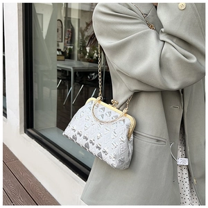 Silver evening bag with heart pattern and chain strap worn with olive green blazer