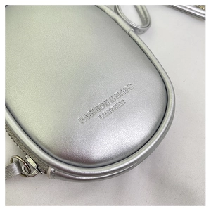 Primer plano del mini bolso plateado con textura de cuero y texto en relieve