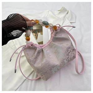 Détail de la texture jacquard rose et de la poignée en perles colorées du sac à main