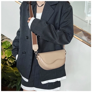 Detail of nude saddle bag with wave-shaped flap and brown-white woven canvas strap