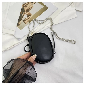 Detalle de mini bolso ovalado negro con cadena de bolas plateada sostenido a mano