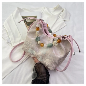 Détail du sac dumpling en brocart rose avec broderie traditionnelle et poignée perlée