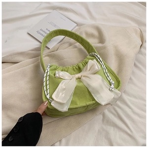 Detailed texture of green corduroy handbag with a large decorative white satin bow