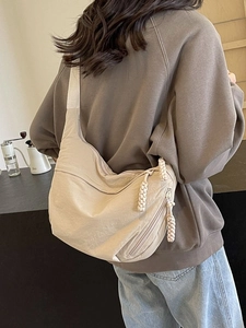 Sac bandoulière minimaliste en nylon beige en forme de demi-lune porté par un modèle