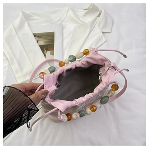 Détail du sac en dentelle rose avec cordon de serrage et poignée en perles colorées