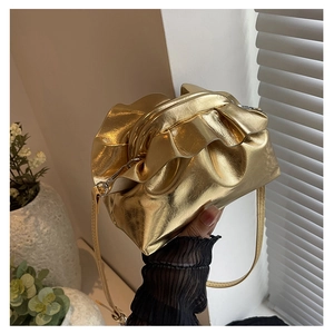 Detail shot of a shiny gold metallic pleated cloud bag held by hand in a bright room