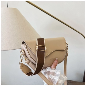 Close-up of beige leather saddle bag with brand lettering and dual shoulder straps